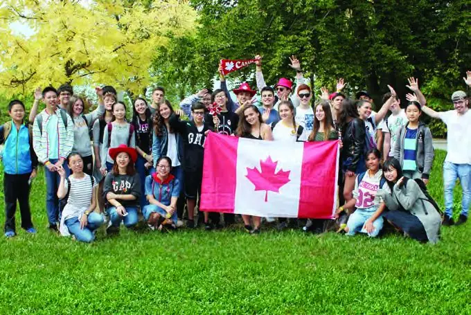 International students holding a Canadian flag together outdoors in Richmond.