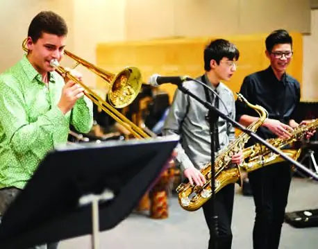 Secondary school students playing trombone and saxophone in a jazz band.