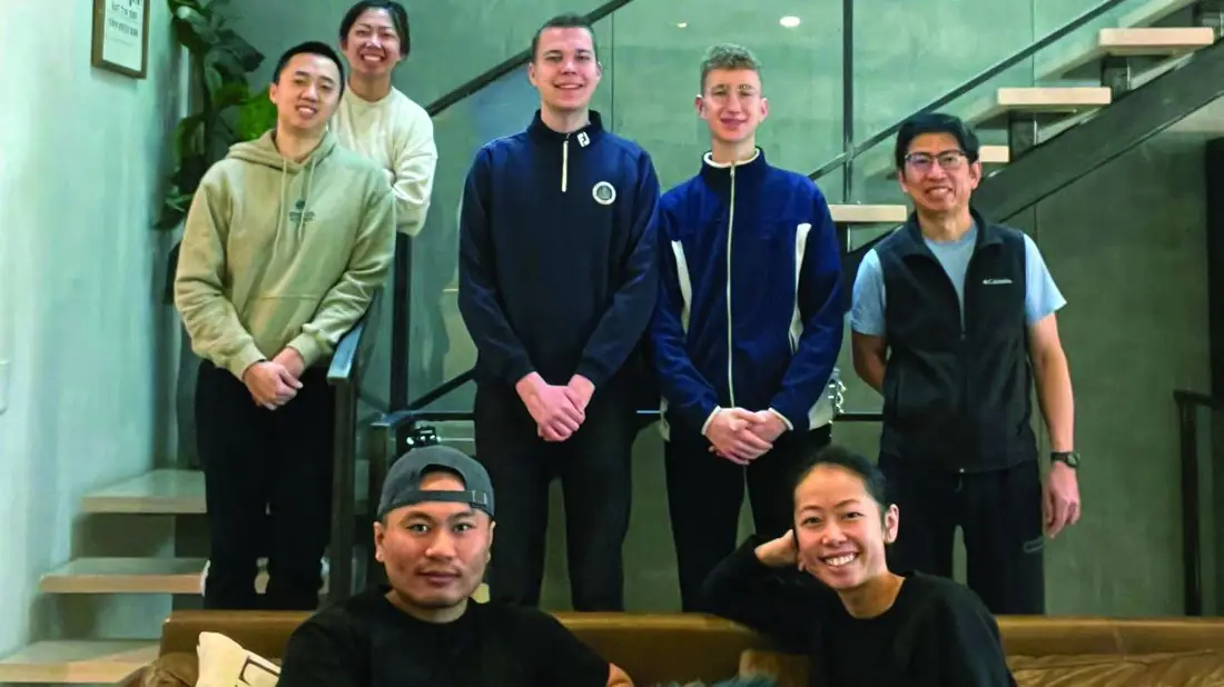 A group of students and homestay hosts gathered together on a staircase at home.