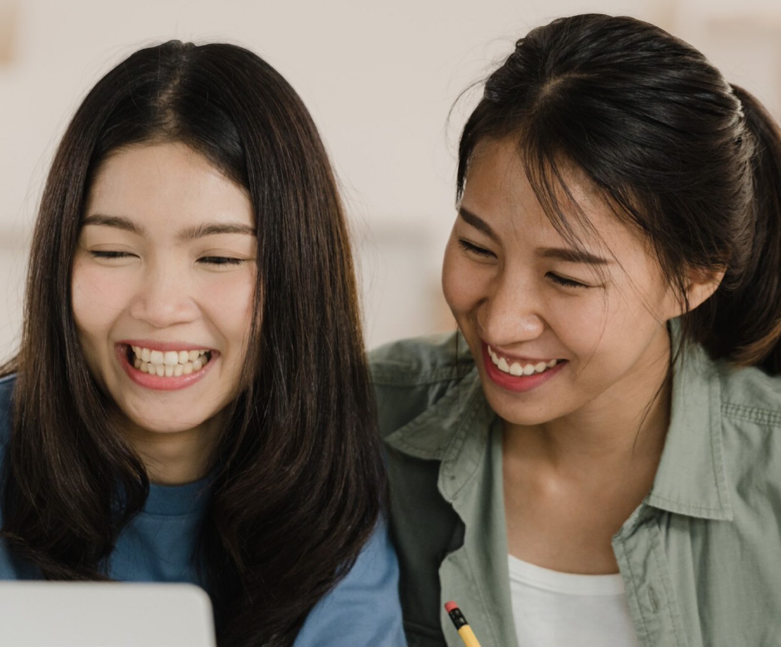 Two young women laughing while looking at a laptop together